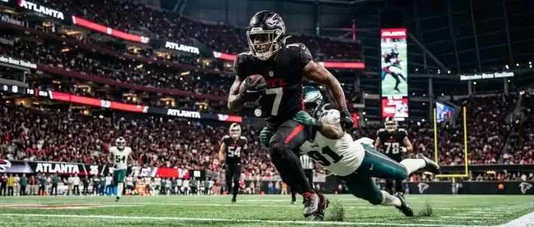 Bijan Robinson breaking a tackle during a night game for the Atlanta Falcons.